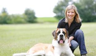 Kristina Ziemer-Falke sitzt auf einer Wiese neben einem großen Hund.